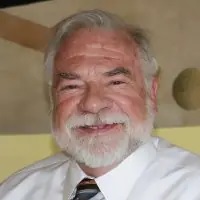 a man with a beard is wearing a white shirt and tie and smiling
