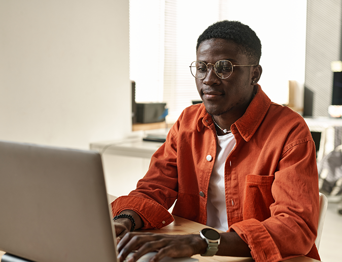 a man wearing glasses is typing on a laptop